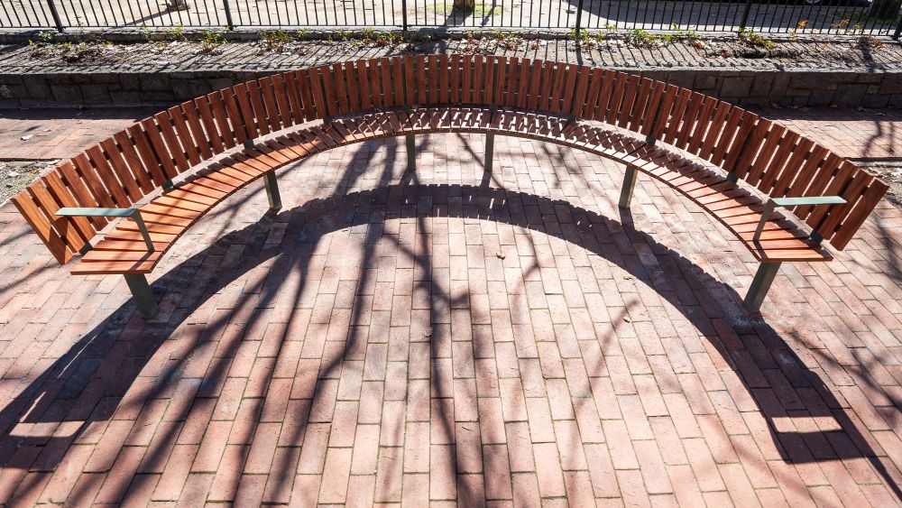A large curved wooden seat in a park.