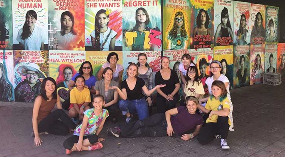 female street artists in front of their mural